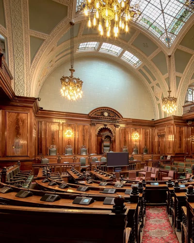 A legislative chamber with rows of wooden desks
